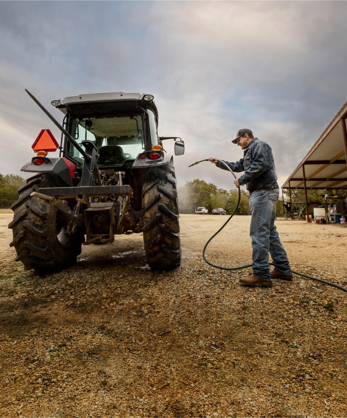 Farmer hosing down small tractor