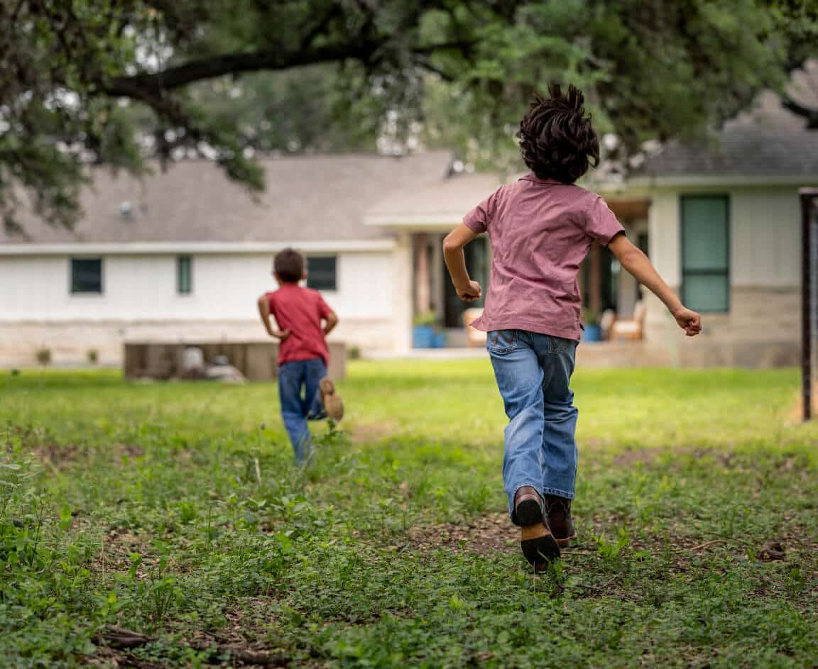 2 children running in their backyard